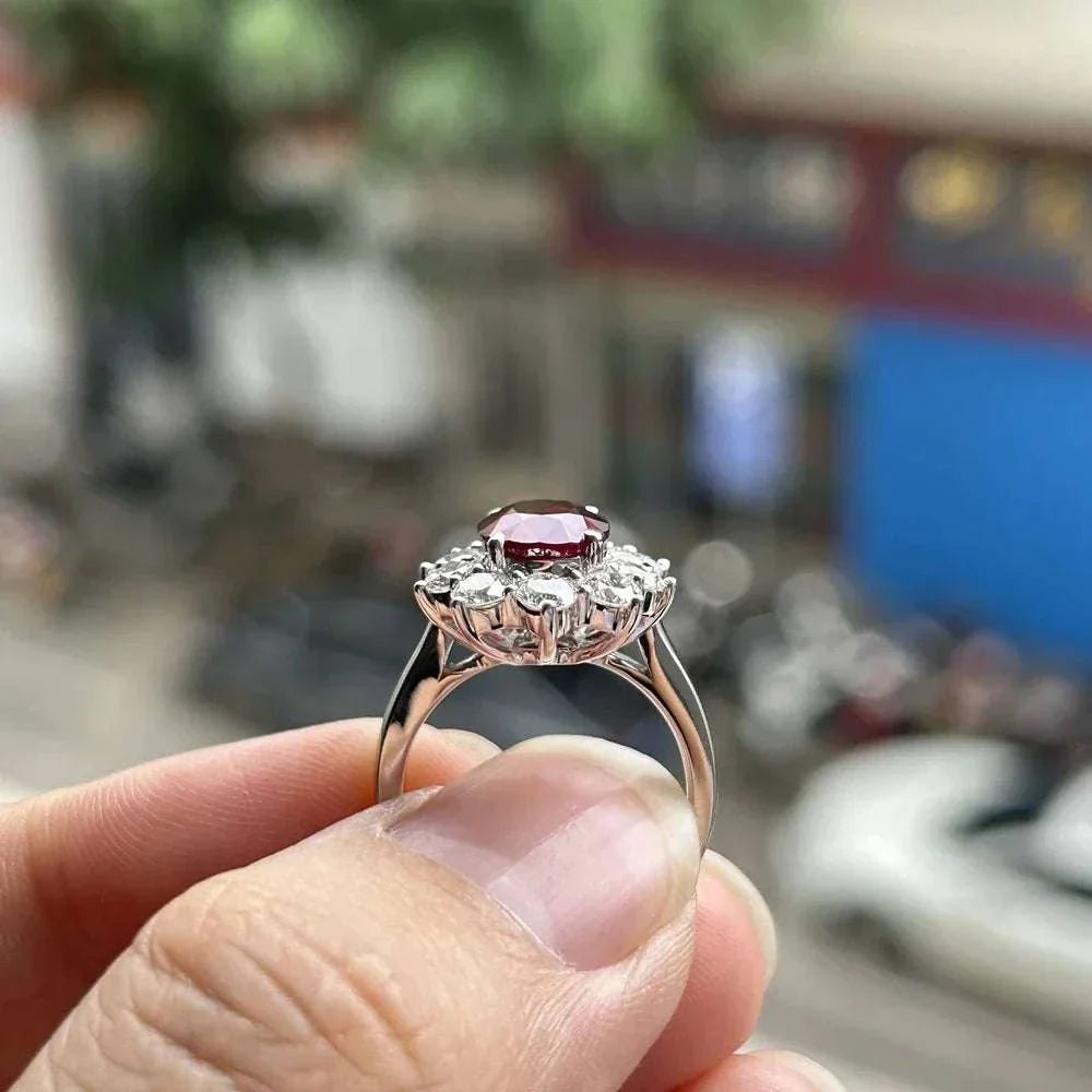 3 carat Mozambique ruby ring with diamonds in 18K white gold setting held between fingers