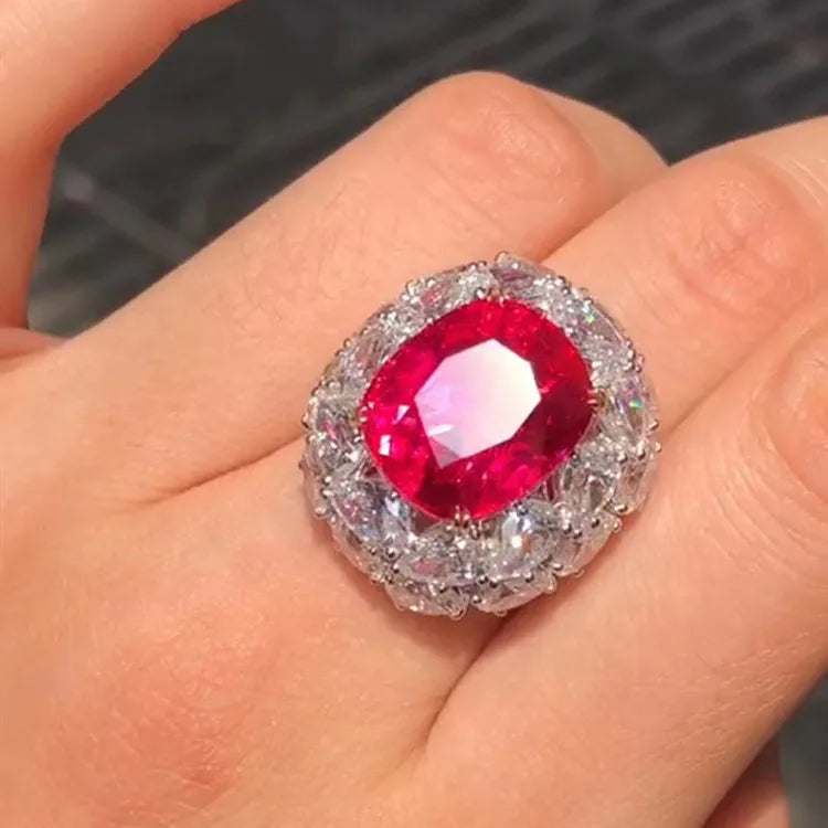 Close-up of a hand wearing the Crimson Star of Mogok ring featuring a vibrant 14.54ct neon red Jedi Spinel surrounded by sparkling diamonds.