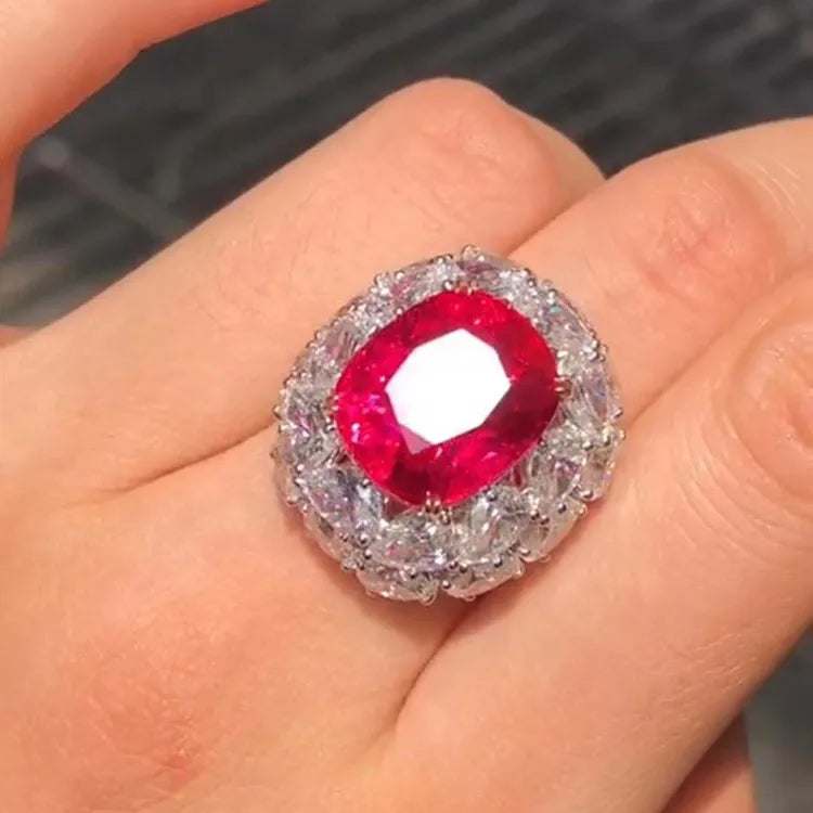 Close-up of a hand wearing the Crimson Star of Mogok ring featuring a 14.54ct neon red Jedi Spinel surrounded by sparkling white diamonds.