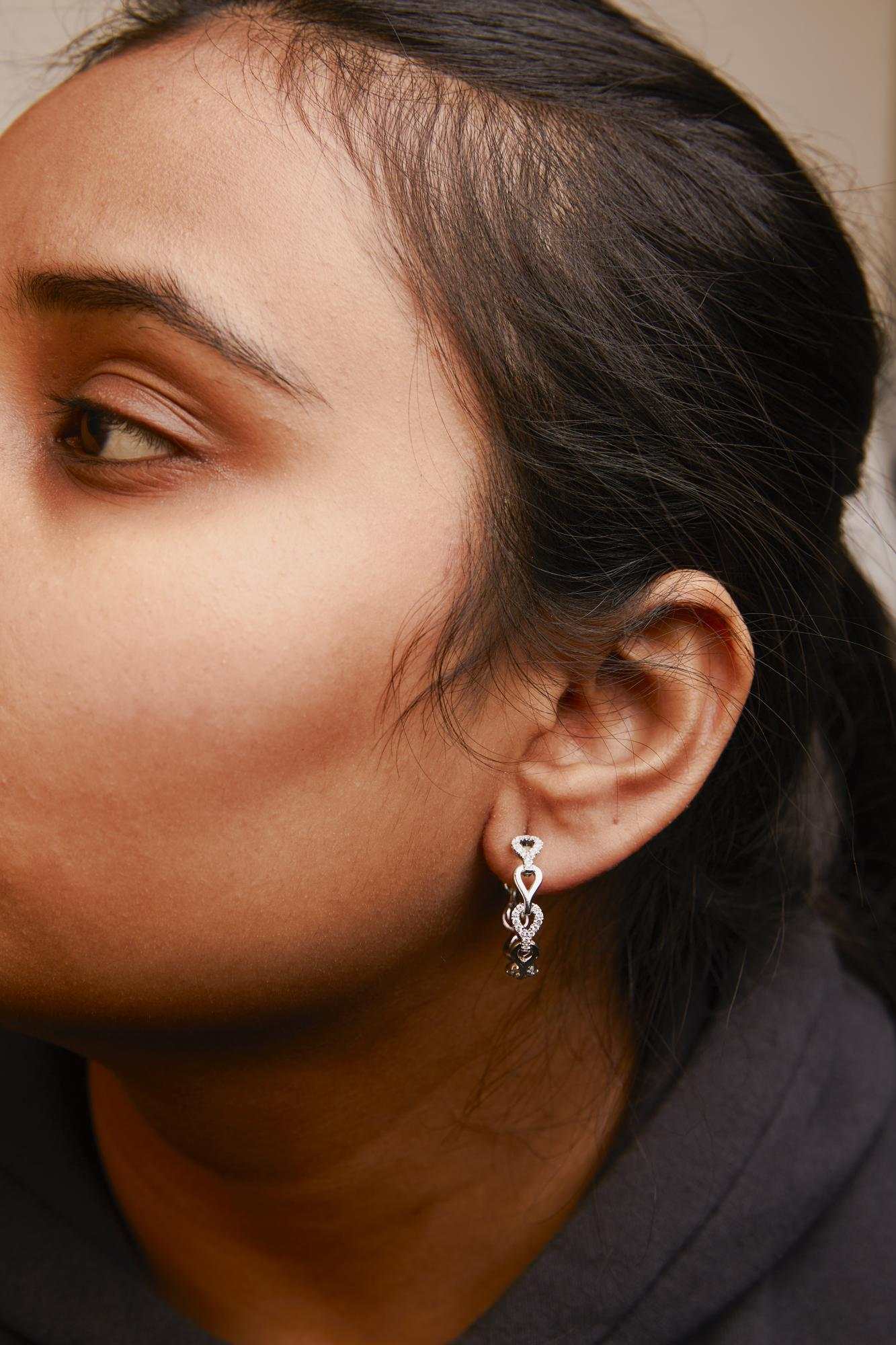 Close-up of a woman wearing 14K white gold Diamond Open Link Hoop Earrings with heart link design and sparkling round diamonds.