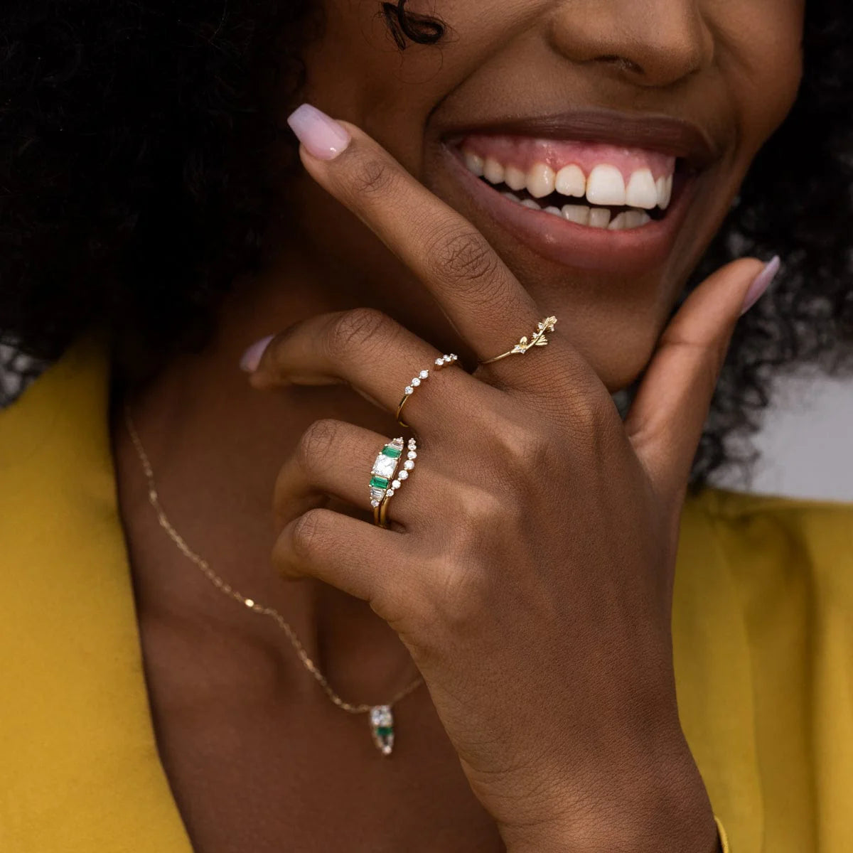 14k yellow gold Hall of Emerald Ring with natural emeralds and Asscher-cut diamond on a smiling hand