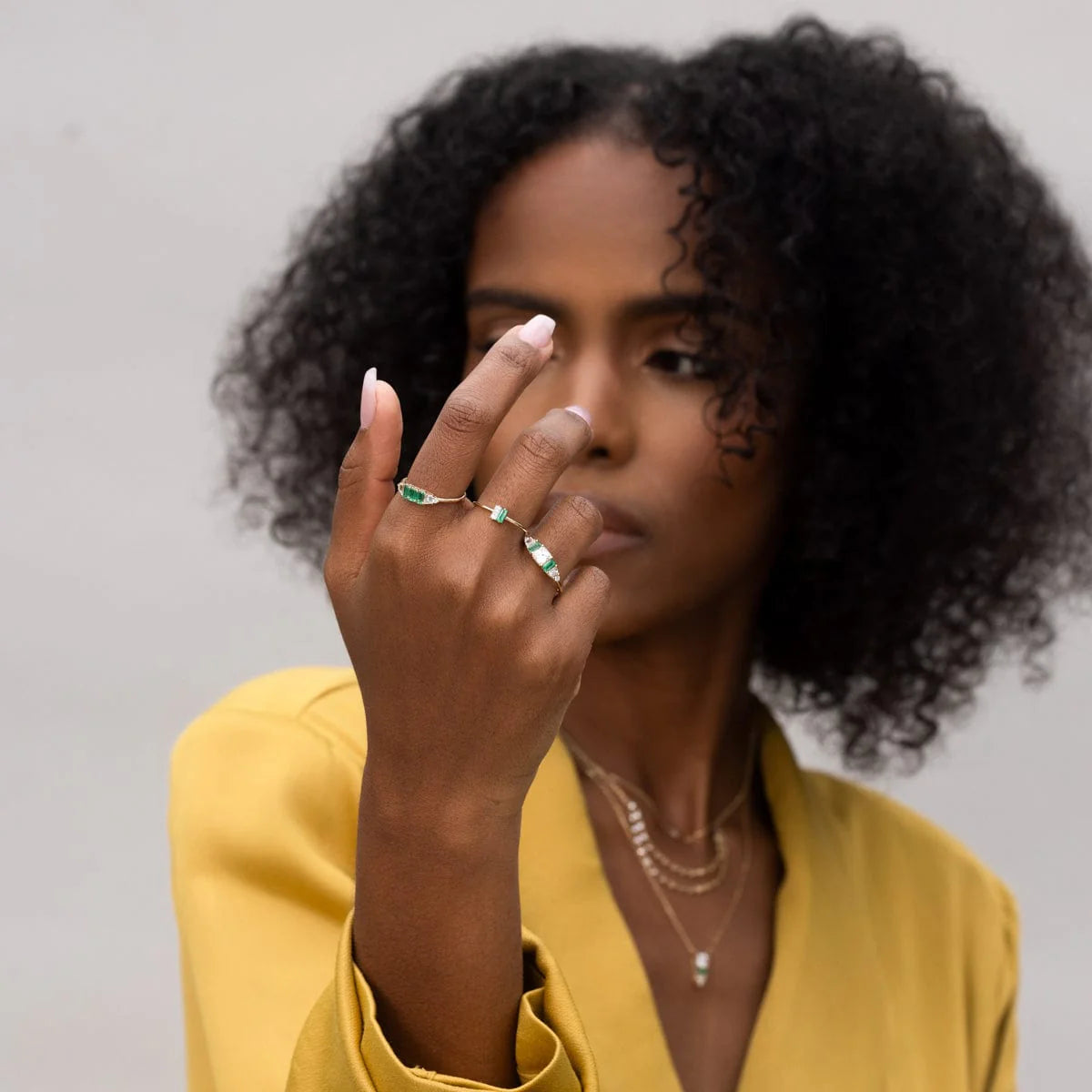 Woman wearing 14k yellow gold Hall of Emerald Ring with natural emeralds and diamonds on hand