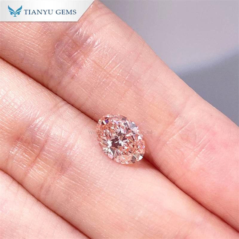 Close-up of a cherry pink pear oval lab grown diamond on a fingertip, 1.1.99 carats
