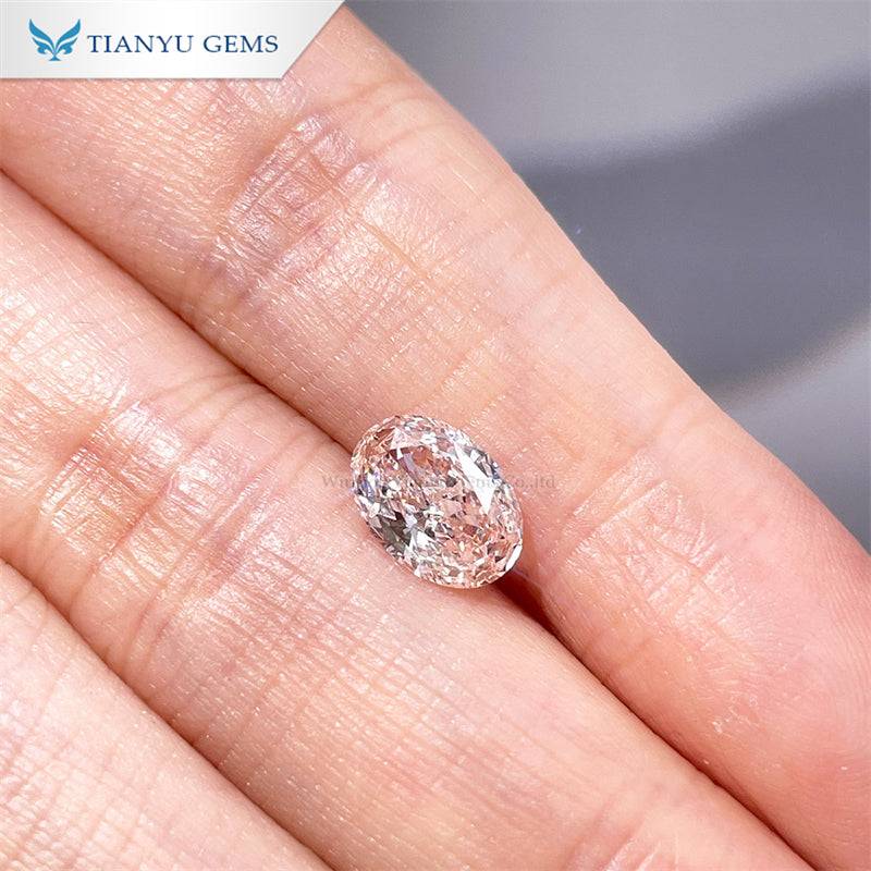 Close-up of an oval-shaped lab grown diamond held between fingers, showcasing its clarity and facets
