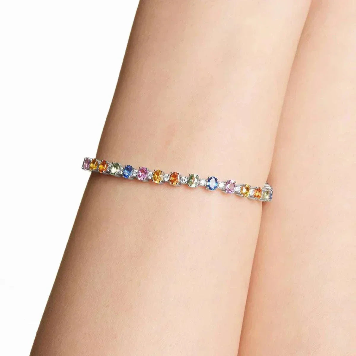 Close-up of a multicolored gemstone tennis bracelet worn on a wrist, featuring a delicate and elegant design.