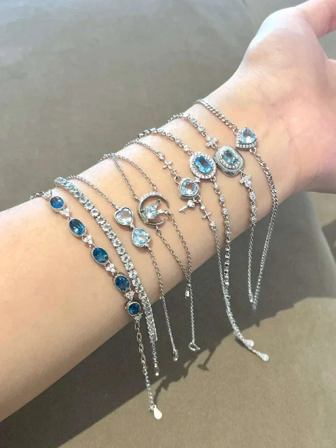 Silver chain bracelets with blue and clear gemstone accents displayed on a wrist