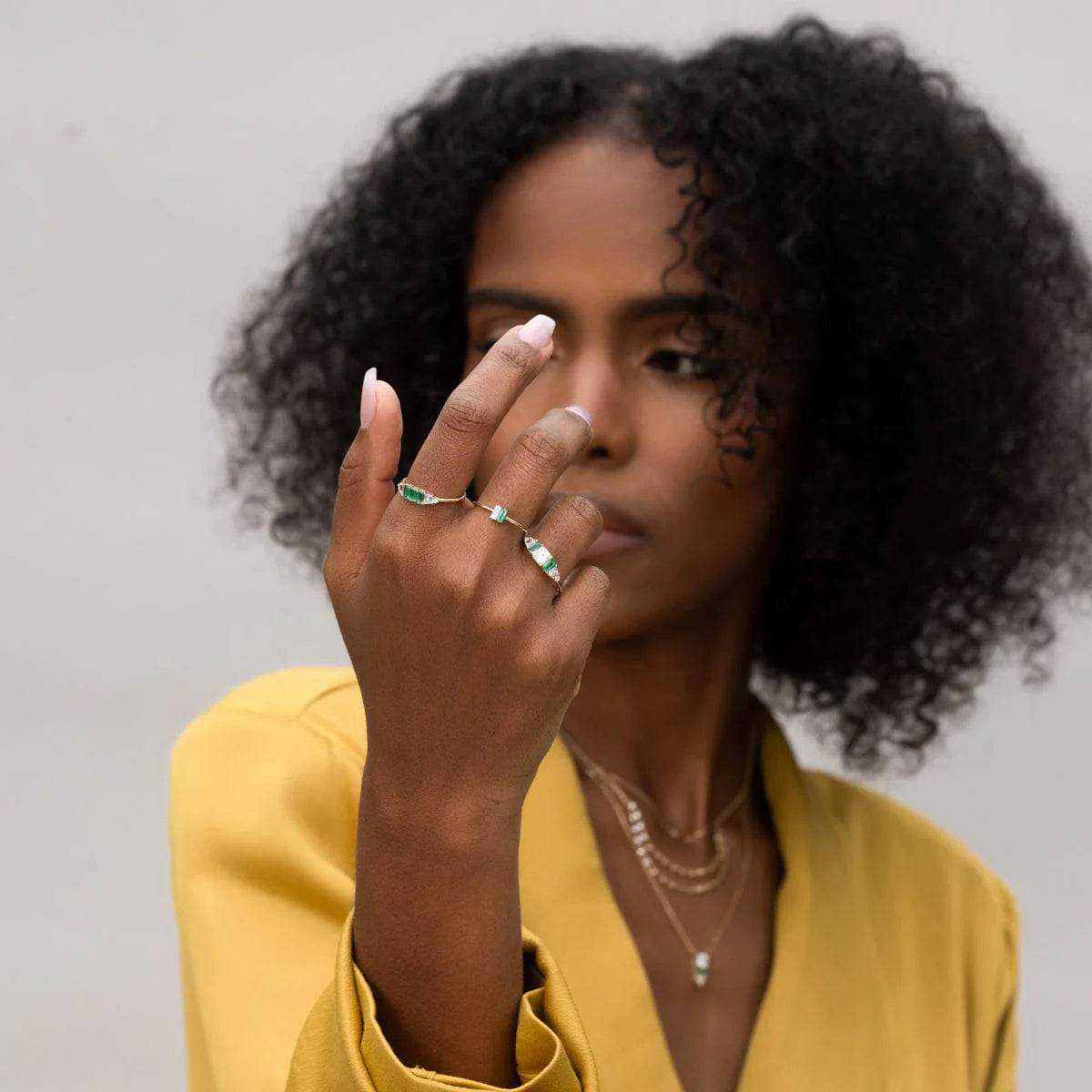Elegant Hall of Emerald Ring on woman's hand, featuring 14k yellow gold, diamonds, and emeralds.