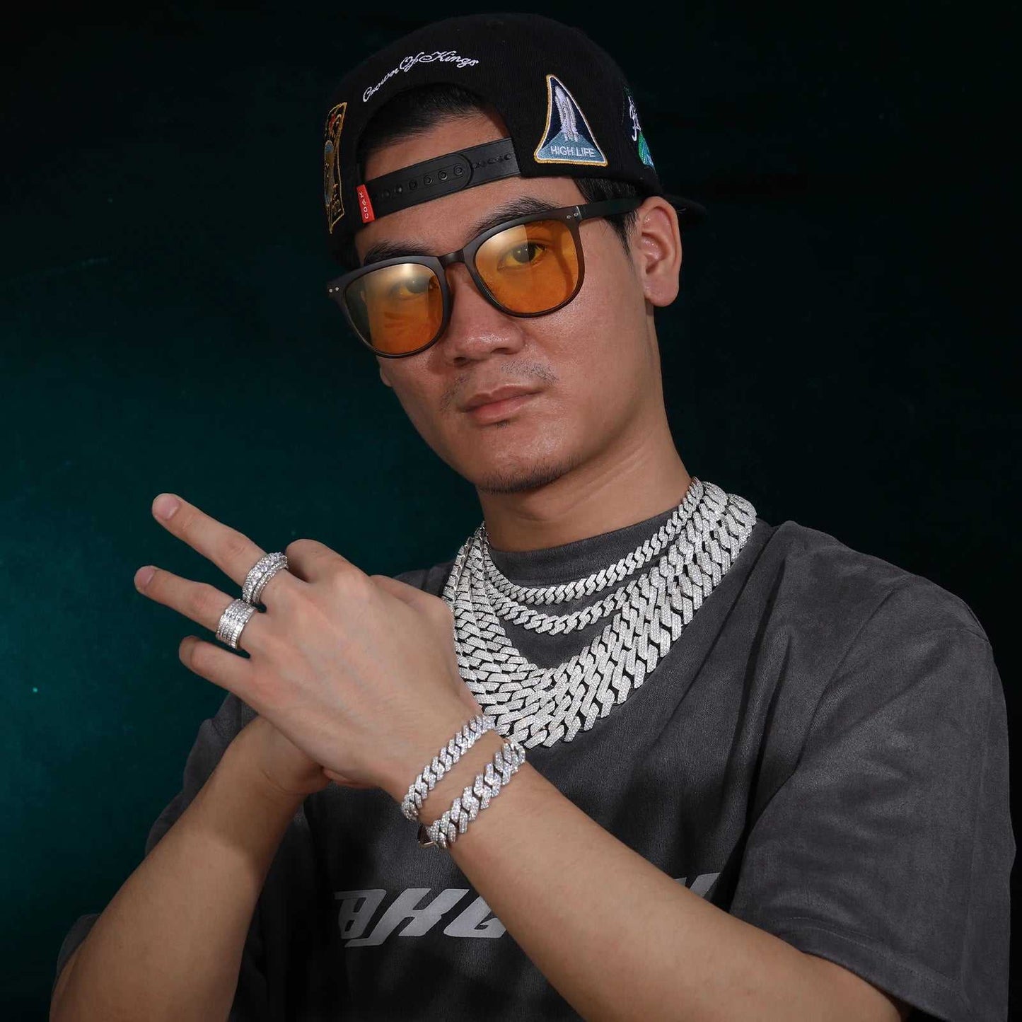 Man wearing multiple 925 sterling silver VVS moissanite Cuban link chains, bracelets, and rings with hip hop style accessories