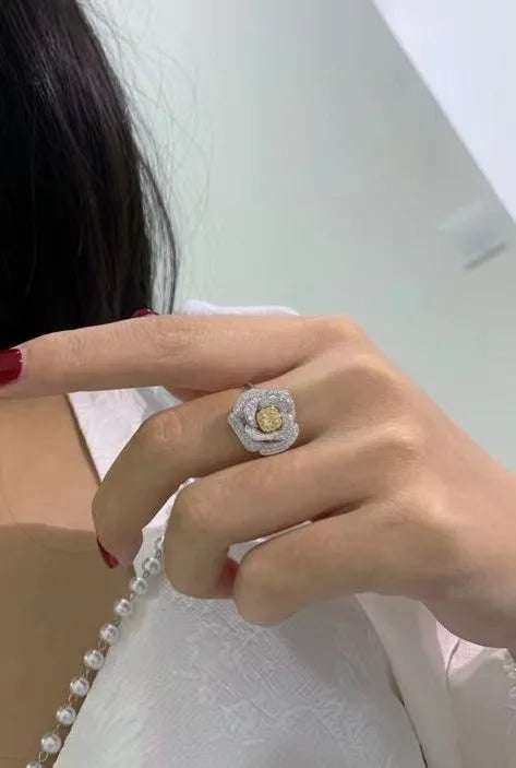 Close-up of a hand wearing a Valentine Love Serial Rose Jewelry Set diamond rose ring with gold and silver details.