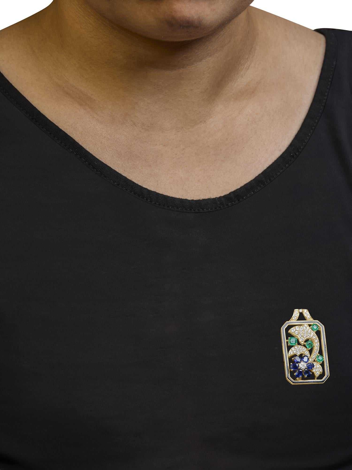 Convertible 18K yellow gold Oceanheart Sigil pendant brooch with dolphin silhouette, diamonds, sapphires, and emeralds on black top.