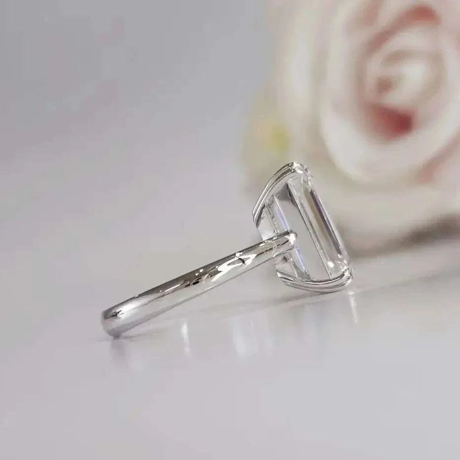 Eternity Prism ring featuring a 5ct emerald-cut diamond in a sleek silver setting with a blurred rose background
