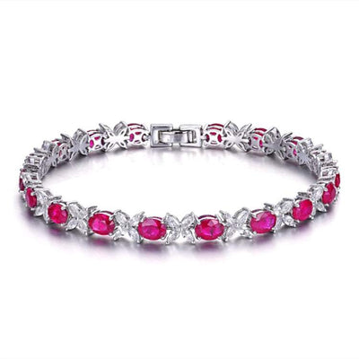 18k gold bridal bracelet featuring vibrant oval Myanmar rubies and intricate silver floral accents, inspired by the Dragon’s Heart of Eldoria legend.