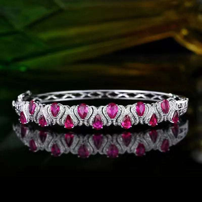 18k gold bracelet featuring pear-shaped Mozambique rubies with intricate silver detailing, inspired by the Elven Queen’s Heartfire legend.