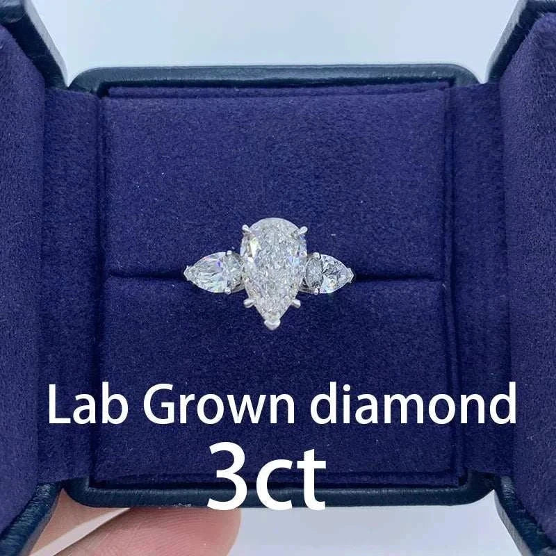 The Aurelia Sigil pear-shaped 3-carat lab-grown diamond ring with side stones in a navy blue velvet box