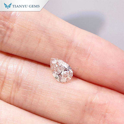 Close-up of a cherry pink pear oval lab grown diamond on a fingertip, showcasing its clarity and shape.