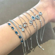 Silver chain bracelets with blue and clear gemstone accents displayed on a wrist