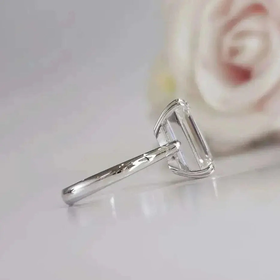 Eternity Prism ring featuring a 5ct emerald-cut diamond in a sleek silver setting with a blurred rose background