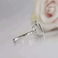 Eternity Prism ring featuring a 5ct emerald-cut diamond in a sleek silver setting with a blurred rose background