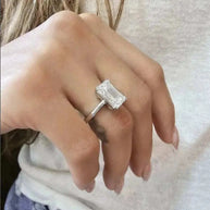 Close-up of a hand wearing the Eternity Prism 5ct emerald-cut diamond ring with a simple silver band
