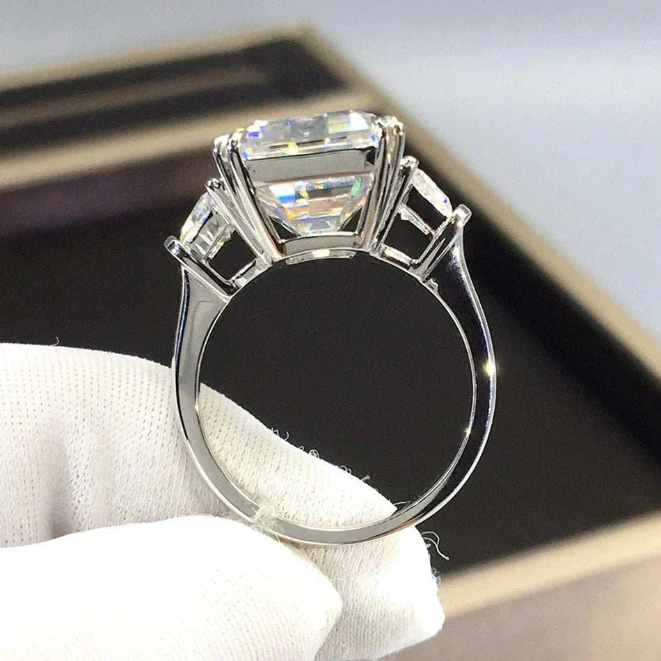 Close-up of the Celestial Flame of the Archmage ring featuring a large 10ct moissanite centerpiece with two smaller side stones in a polished silver setting, held by a gloved hand.