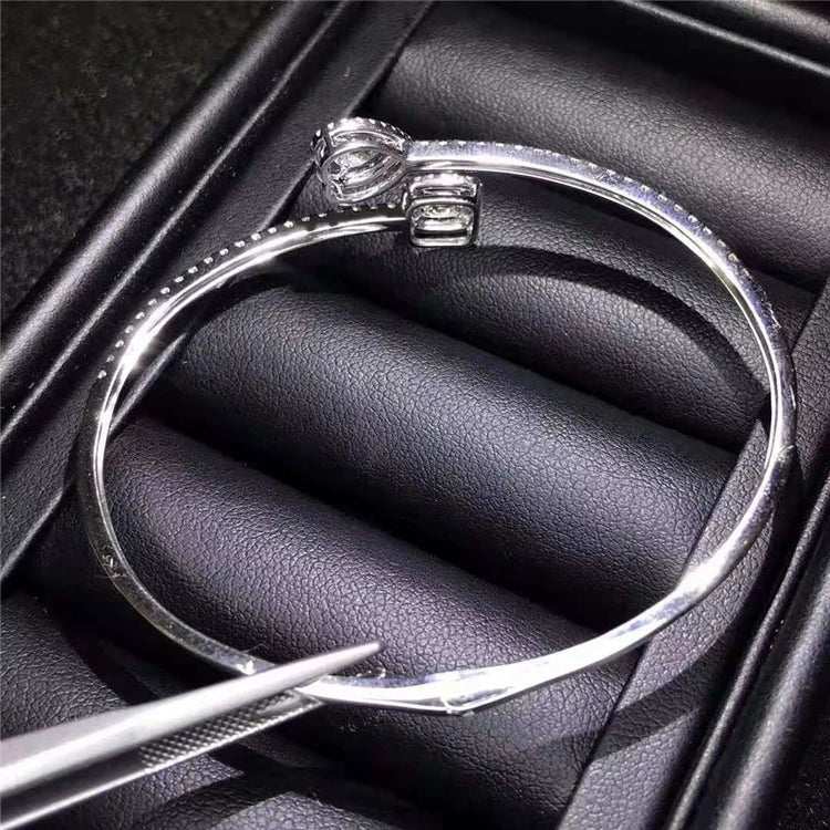 Silver bangle bracelet with a single large diamond charm in a black jewelry box