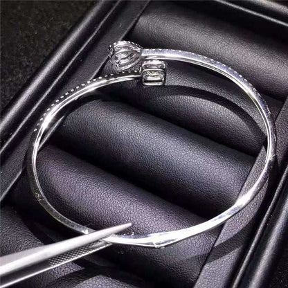 Silver bangle bracelet with a single large diamond charm in a black jewelry box